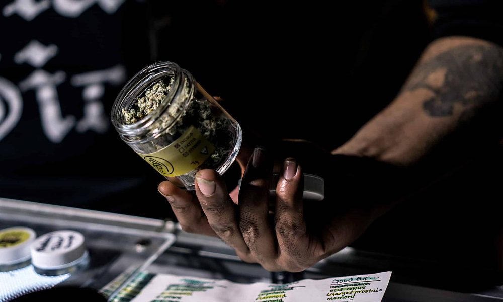 A Vendor Showing Off A Jar Of Cannabis Flowers