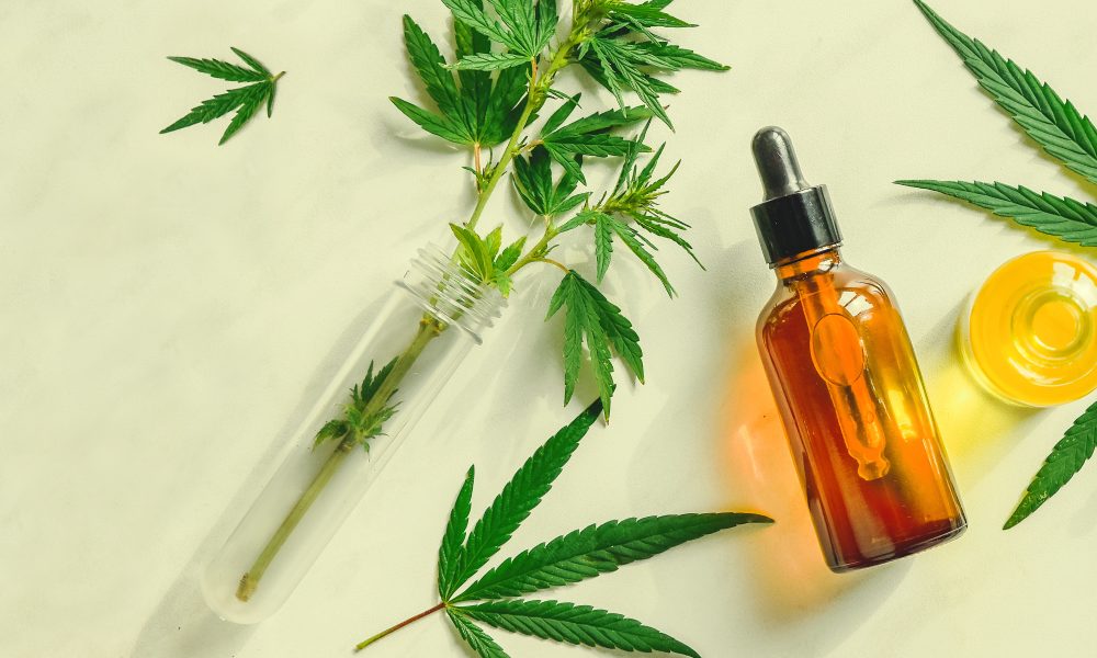 Different glass bottles with CBD OIL, THC tincture and cannabis leaves on yellow background. Flat lay, minimalism. Cosmetics CBD oil.